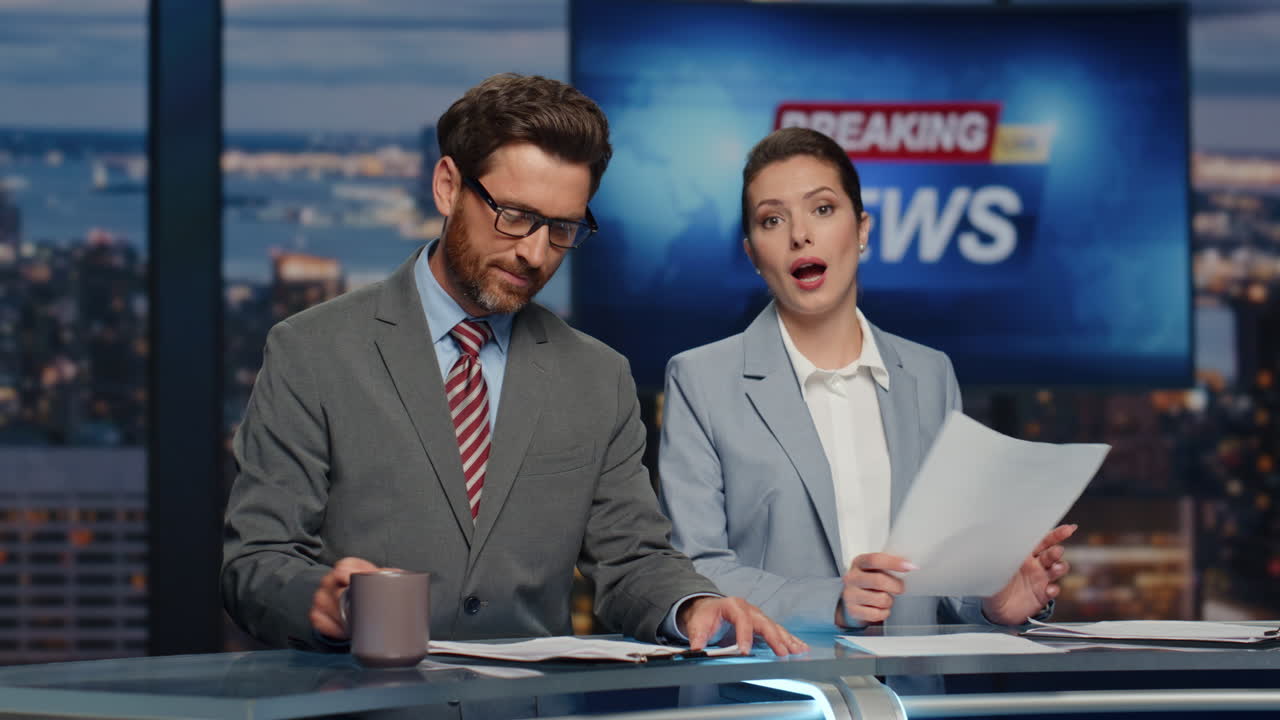Primer plano de presentadores felices transmitiendo noticias en un estudio nocturno. Presentadores de noticias informando