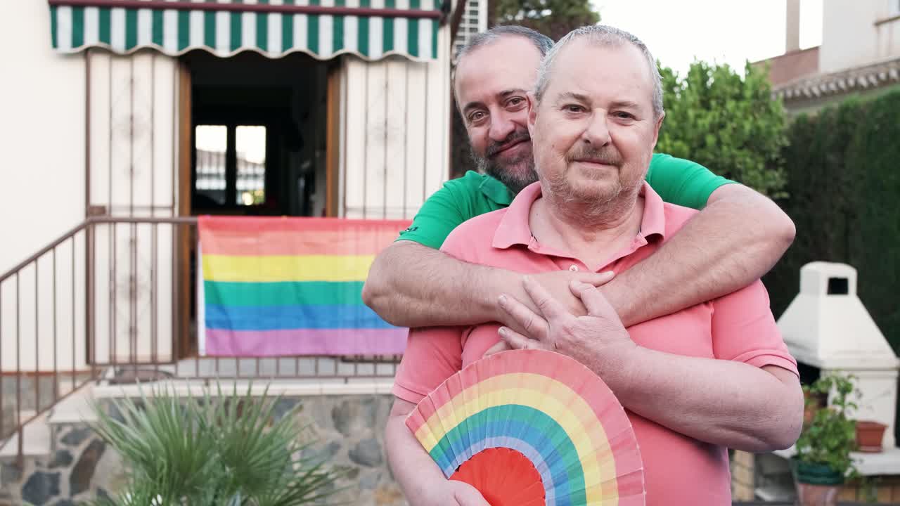 Gay couple embracing with rainbow flag