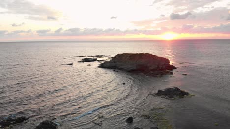 Toma-Aérea-De-Un-Dron-Sobre-Un-Joven-Disfrutando-Del-Amanecer-En-Las-Rocas-En-El-Mar-Cerca-De-Lozenets,-Bulgaria