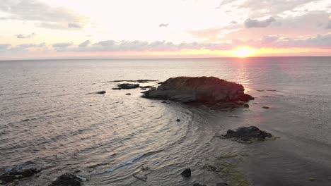 toma aérea de un dron sobre un joven disfrutando del amanecer en las rocas en el mar cerca de lozenets, bulgaria