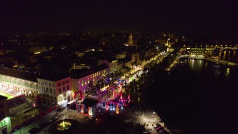 Night-aerial-over-colorful-illuminated-bustling-Split-Riva-waterfront,-Croatia