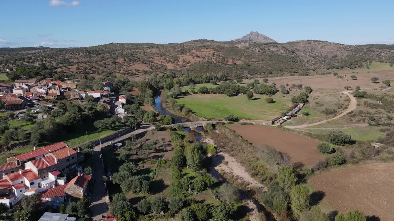 un dron vuela hacia adelante mientras desciende sobre un antiguo puente romano y una ciudad fluvial
