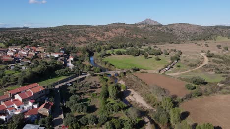 a drone flies forward as it lowers itself over an ancient roman bridge and river town