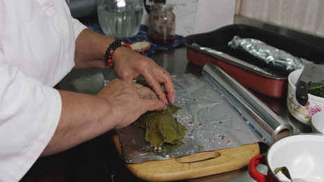 wrapping seasoned raw trout fish in herb leaves and baking tin foil