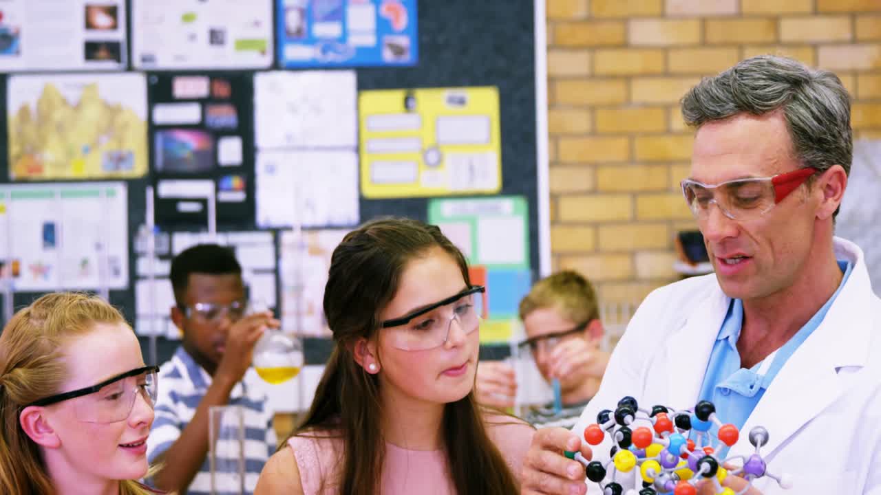 학교 선생님이 분자 모델 4k에 대해 학교 아이들을 돕고 있습니다.