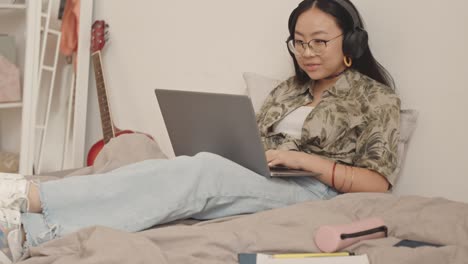 asian teenage girl with laptop in bed