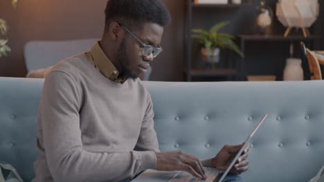 young man working on laptop on a couch