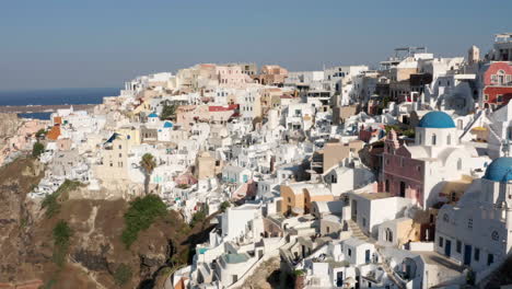 Hermosas-Casas-En-El-Pueblo-Costero-De-Oia-En-Un-Día-Soleado-En-Santorini,-Grecia