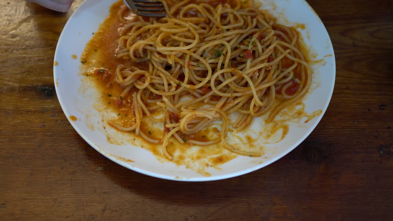 작은 소녀가 레스토랑에서 토마토 해산물 스파게티를 먹습니다.