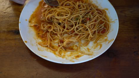 a little girl eats tomato seafood spaghetti in a restaurant. over look.