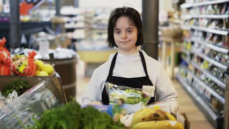 Porträt-Eines-Mädchens-Mit-Down-Syndrom,-Das-Einen-Einkaufswagen-Mit-Frischem-Gemüse-Schiebt,-Um-Die-Regale-Aufzufüllen