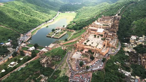 Toma-Aérea-Del-Castillo-Histórico-Situado-En-La-Cima-De-La-Colina-Con-Vegetación-Verde-Y-Lagos-India-Rajasthan