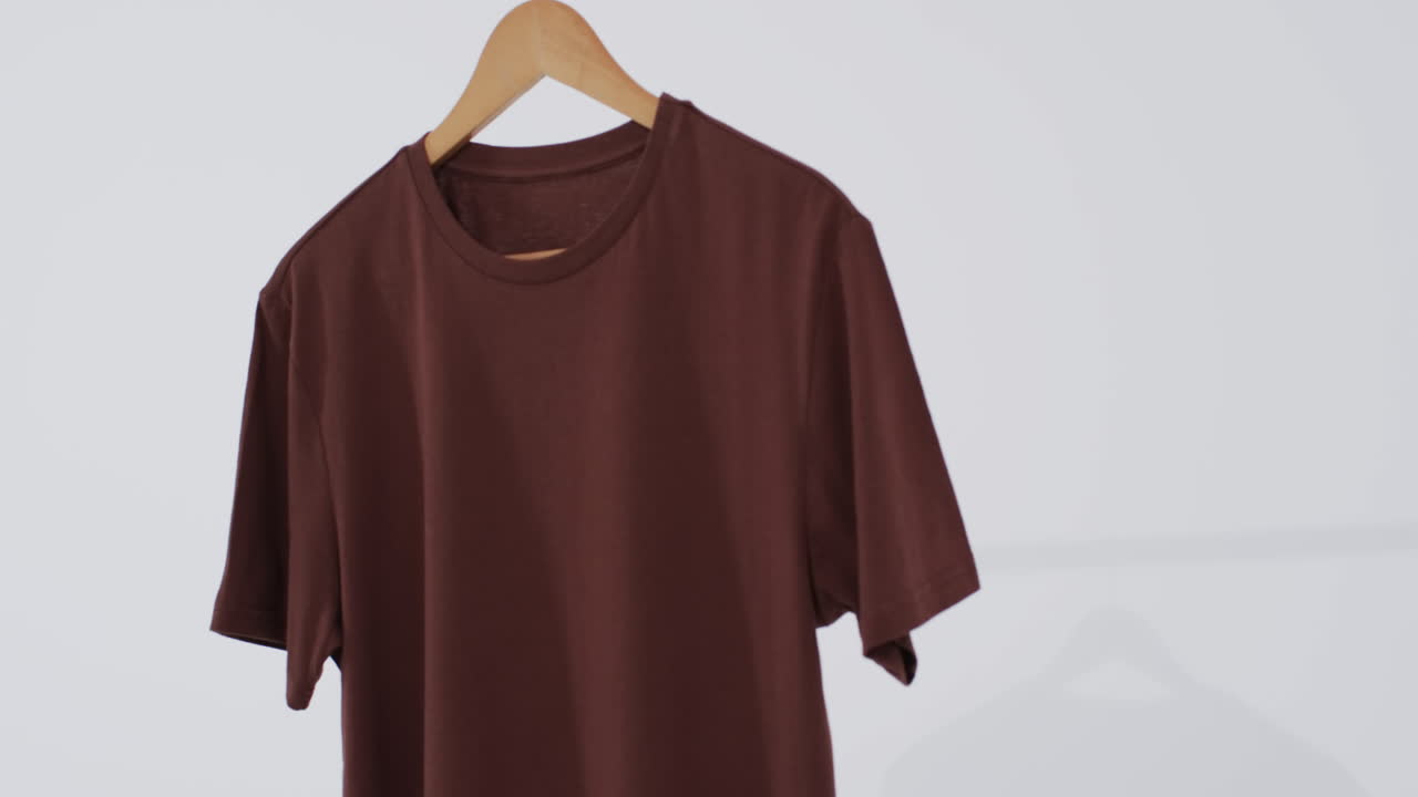 Video de camiseta marrón en percha y espacio para texto sobre fondo blanco