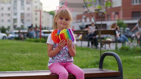 Child-girl-kid-showing-many-colorful-squishy-silicone-bubbles-sensory-toy,-kid-playing-pop-it-game