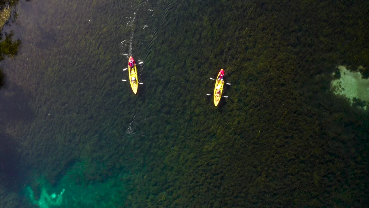 Aerial shot following two kayaks floating down the crystal clear Rainbow River