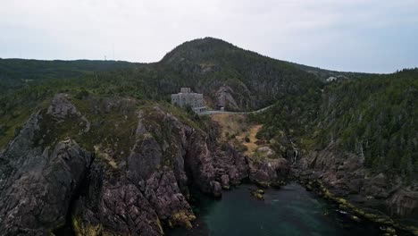 a drone shot showing a small castle nestled in the rocky hills of logy bay in newfoundland canada.