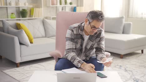 Focused-middle-aged-man-holding-shopping-and-debt-bills.