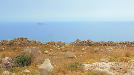 stone wall at the seashore with distant view of historic fortress in the middle of the sea