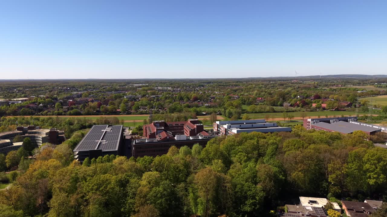 Veduta aerea di un quartiere residenziale tedesco con alberi primaverili colorati, case ed edifici per uffici. Scena di sorvolo tranquilla che mostra strade residenziali, aree verdi e sviluppo moderno in Germania.