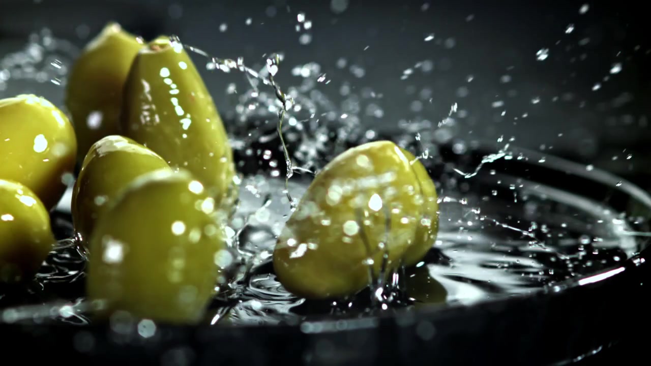 Olive verdi fresche che cadono nell'acqua con schizzi