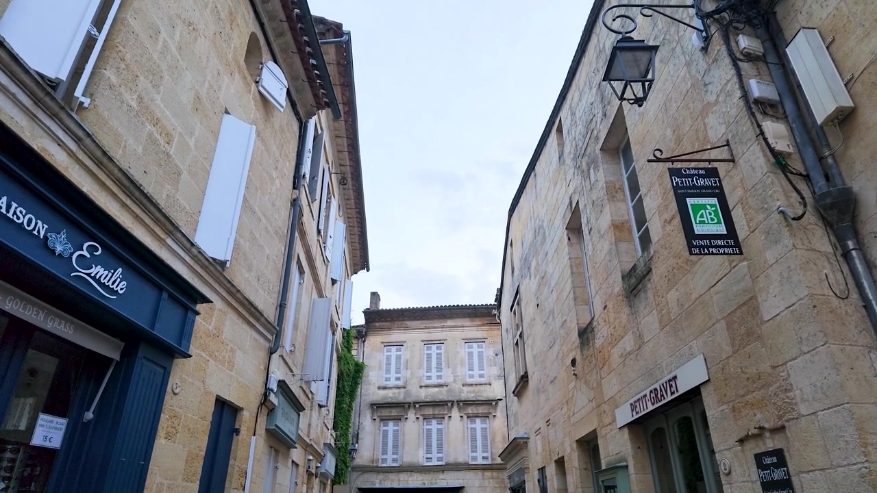 Ripresa a mano a bassa angolazione di architettura tradizionale francese con facciate in pietra e persiane in legno.