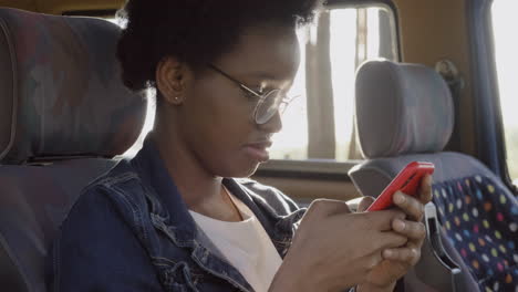 Una-Mujer-Joven-Escribiendo-En-Su-Teléfono-Celular-Durante-Un-Viaje-Por-Carretera-En-La-Caravana