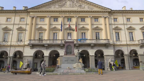 a slow-mo close-up view of the large building with a porch and the tourists of the town hall, aosta valley, italy.