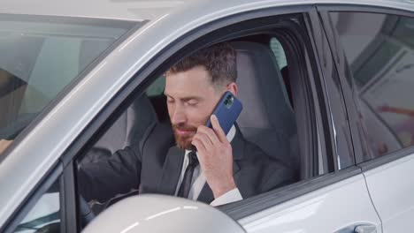 hombre feliz en traje hablando en móvil mientras examina el coche