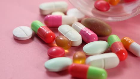 assorted pills and capsules on pink surface