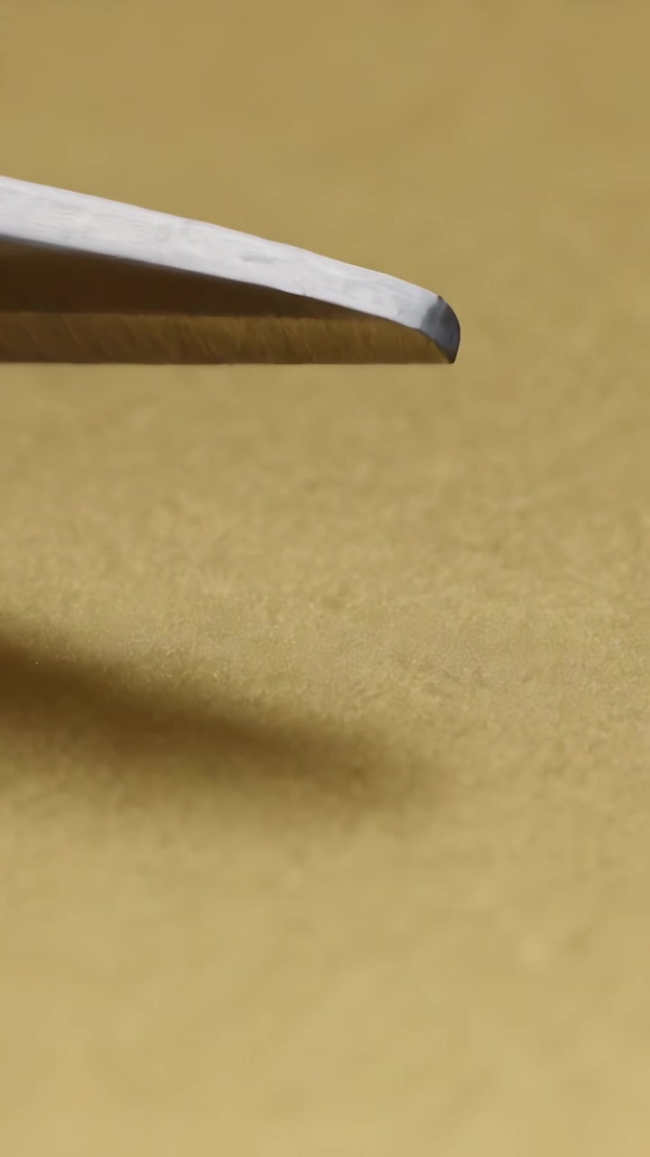 Vertical video: Sliding slim white tool lowering across beige paper surface, casting soft shadow
