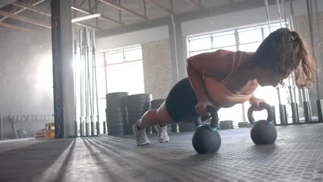 performing push-ups using kettlebells, woman exercising in gym for fitness, copy space
