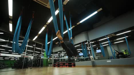 attractive woman doing aero yoga stretching exercises in hammocks at fitness studio. healthy lifestyle for female. workout gym