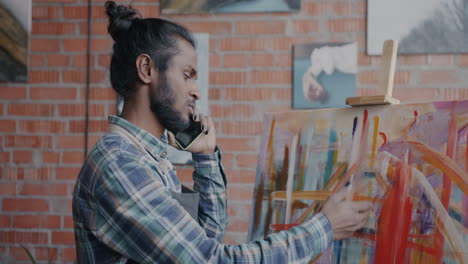 artist talking on phone while working on abstract painting