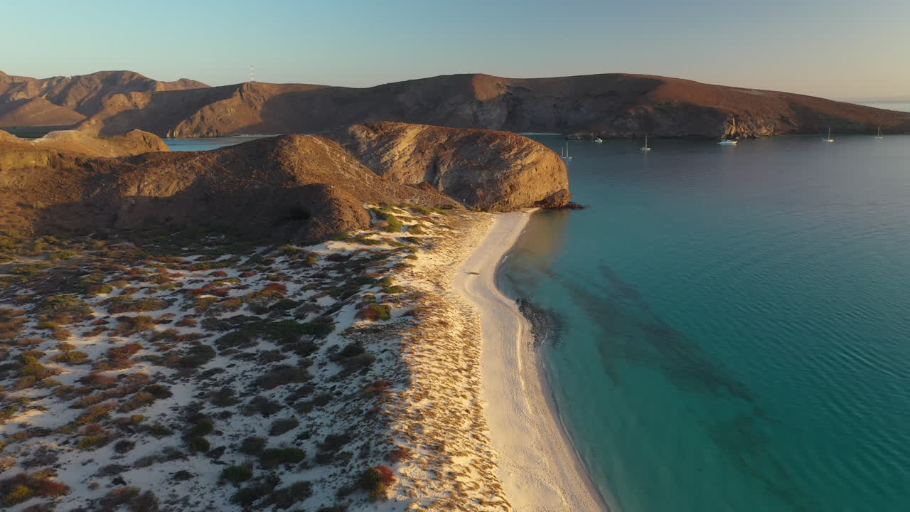 발란드라 해변의 영화 같은 드론 샷, 붉은 언덕, 청록색 바다, 백사장 해변을 지나 일몰 동안 넓게 회전