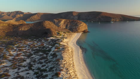 toma cinematográfica de drones de la playa balandra, pasando por las colinas rojas, las aguas turquesas y las playas de arena blanca, girando ampliamente durante la puesta de sol