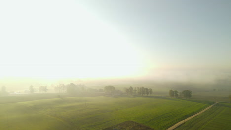 Luftaufnahme-Eines-Einzelnen-Einsamen-Hauses-Auf-Einem-Ländlichen,-Malerischen-Ackerlandfeld-Während-Des-Dunstigen-Sonnenaufgangs