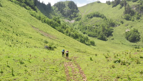 low-aerial-of-Two-hikers-walking-through-a-beautiful-Swiss-landscape