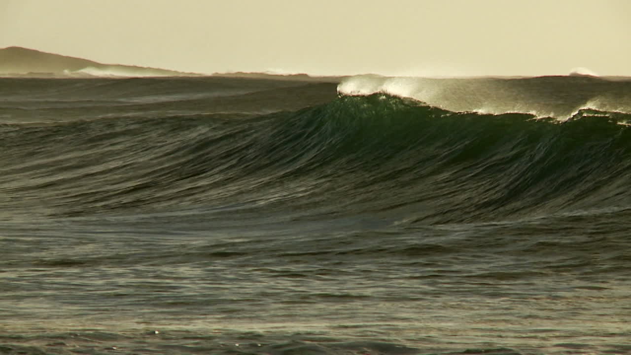 grandes olas llegan a la cima y rompen en la costa