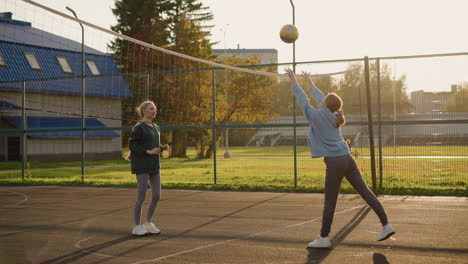 athlete in sportswear playing volleyball with ball, background features open field and blurry view of someone pushing bicycle, with volleyball net visible in foreground