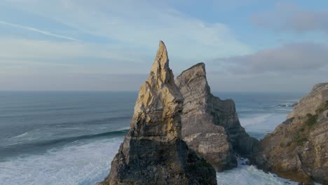 massive standalone rock standing in the atlantic ocean at sunset