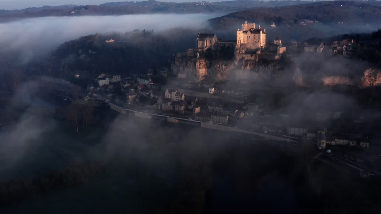 hermosa vista aérea cinematográfica del castillo de beynac sobre la niebla y el río a la luz del amanecer, dordoña, francia, estado de ánimo azul