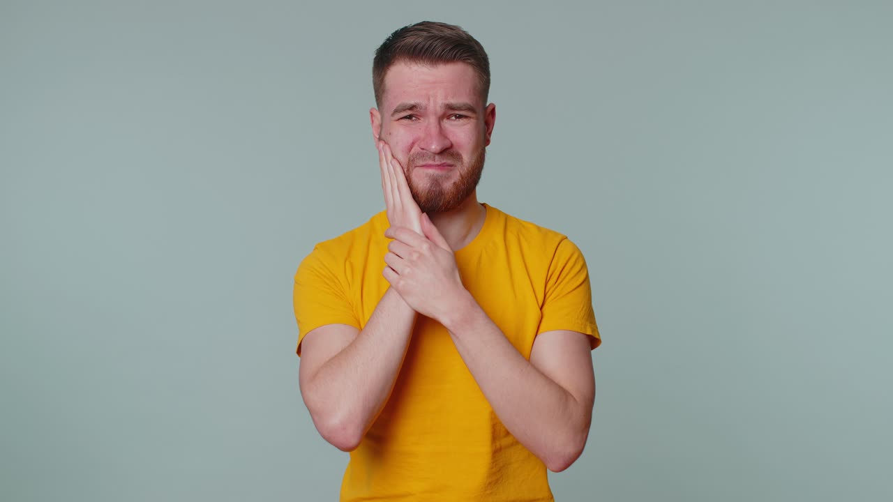 hombre tocando la mejilla que sufre de dolor de muelas, caries o gingivitis esperando una cita con el dentista