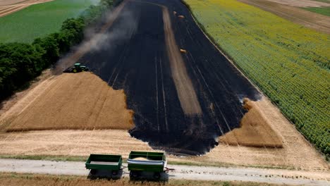 tractor trying to contain the fire on agricultural field - aerial drone shot