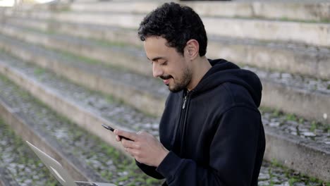 hombre sonriendo y enviando mensajes de texto a través de un teléfono inteligente