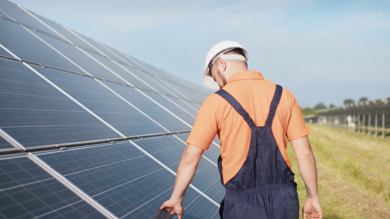 técnico de paneles solares inspeccionando una granja solar