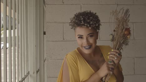 Enclosed-African-American-Woman-Dressed-In-Yellow-Smelling-Dried-Flowers