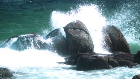 海浪在夏天在海岸附近的岩石上破裂