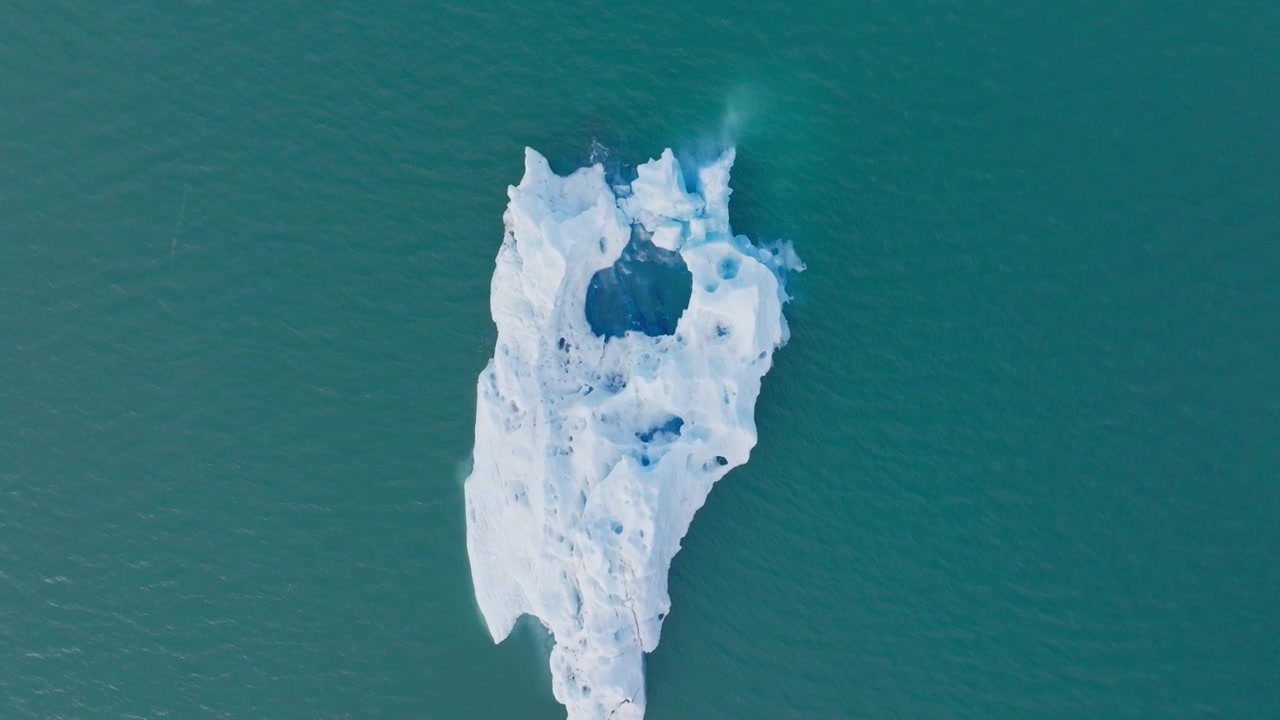 Flygfoto uppifrån och ner av isberg som flyter på turkost sjövatten på Island.