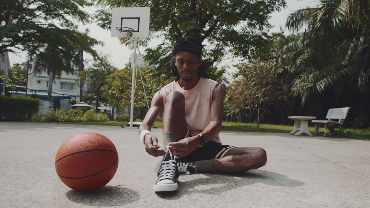Black Streetball Player Tying Shoelaces on Sneakers