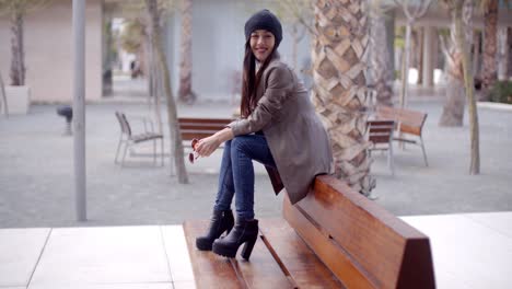 Mujer-Joven-De-Moda-Sentada-Esperando-En-Un-Banco